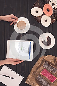 top view of person using digital tablet with social network website on screen and drinking coffee