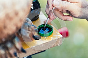 A person dipping a paintbrush in paint to paint a figure made of polystyrene photo