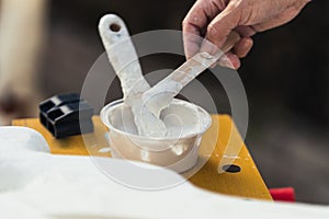 Person dipping white paste with a spatula in a workshop photo
