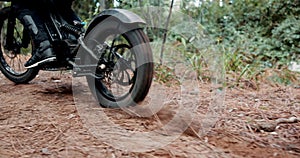 Person, dirt bike and feet on forest trail with tyre spin, speed and start with dust for adventure. Motorcycle, rider