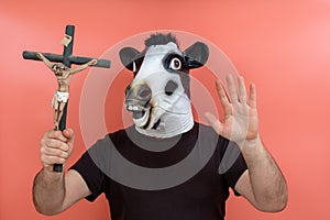 Person disguised in a cow mask holding a crucifix pretending to perform an exorcism