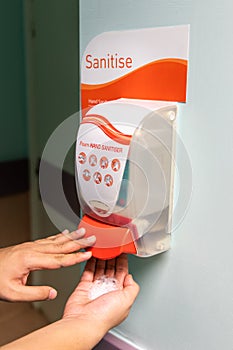 Person dispensing disinfectant sanitizer liquid onto hand at pub