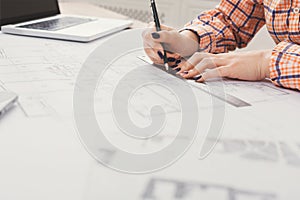 Working on Design Plans at a Table With a Laptop and Drafting Tools in an Indoor Setting