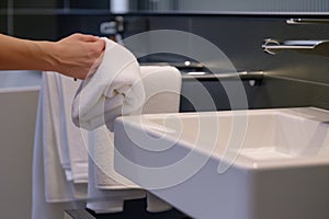 person drying hands with towel on rail next to sink