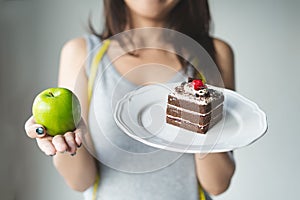 Person eat dessert holding green apple and cake to compare calories as sweet menu to eat during