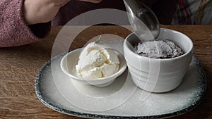 Person, eating chocolate cake and ice cream with spoon, served on a white plate