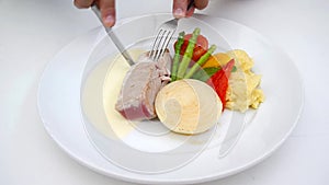 A person eating tuna steak as main dish.