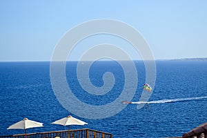 Person is engaged in parasailing, flies on a parachute tied to a boat at high speed on the water at sea in a warm tropical resort