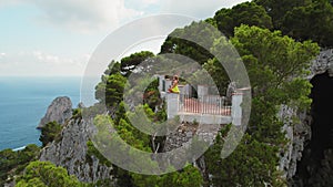 Person enjoying the view from a terrace on cliff of Capri . Woman meditates over the sea on the rocky outcrop.