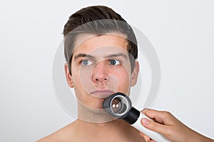 Person Examining Man Face With Dermatoscope