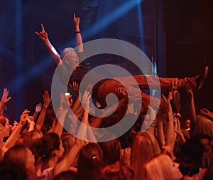 Person, excited and crowd surf at concert, live show and performance for heavy metal band at night. Happy, devil horns