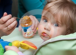 Person feeding baby girl