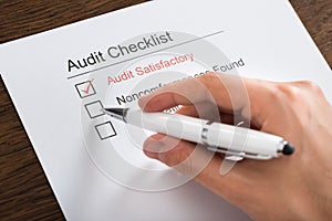 Person Filling Audit Checklist Form At Desk