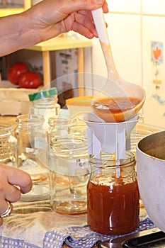 Person filling jars with jam