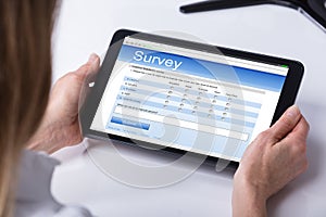 Person Filling Online Survey Form On Digital Tablet