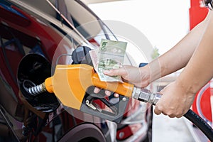 A person is filling up their car with gas and paying with cash. Concept of responsibility and practicality