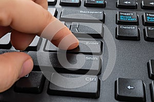 Person finger peessed down the enter key on the black computer keyboard. Distance learning, online work, business and shopping,