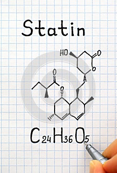 Person fingers with pen writing chemical formula of Statin