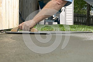 Person finishing wet cement in a backyard project