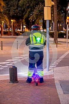 Person with flashing arrow on his back, riding scooted on the street in Barcelona on sunset