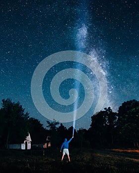 Person with a flashlight and the night sky with Milky Way Galaxy in the background