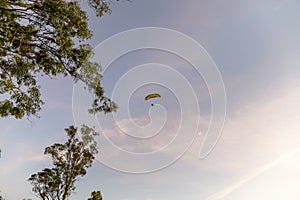 Person flying on a paraglider at sunset.