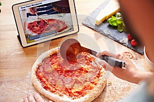 Person Following Pizza Recipe Using App On Digital Tablet