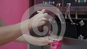 The person gently pours magentacolored ice cream from the machine into a cup