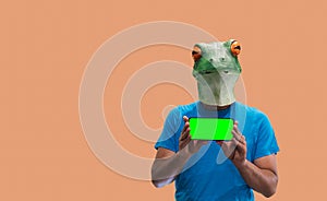 Person gesture with frog mask holding a mobile phone with hands with chroma key screen on orange background