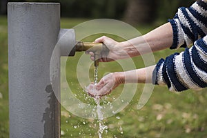 Person gets his hands wet in a water fountain