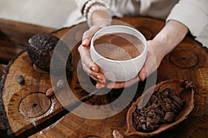 Person giving ceremonial cacao in cup. chocolate drink top view