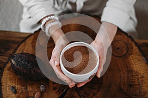 Person giving ceremonial cacao in cup. chocolate drink top view