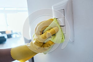 Person With Gloves Disinfecting Light Switches Using Sanitizer