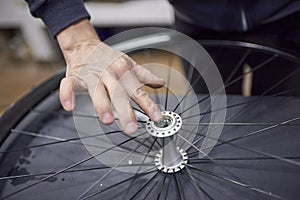 Person greasing the hub of a bicycle wheel while maintenance service