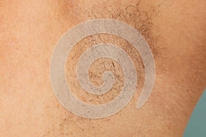 Person with hairy underarms closeup, free copy space, skin background. Arm with armpit hair. Female beauty trend