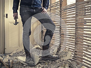 Person with hammer standing by wattle and daub wall