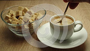 Person hand adding sugar and stirring coffee espresso