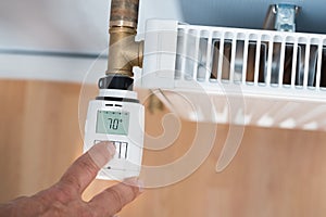 Person hand adjusting temperature on thermostat