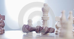 Person, hand and chess piece in defeat on board for king, checkmate or endgame on table at home. Closeup of people