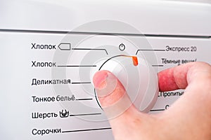 Person hand choosing cycle program on washing machine