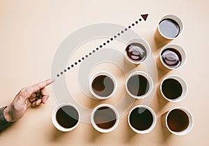 Person hand holding a cup of coffee takeaway surrounded by many coffee paper cup on clean background.drinking and refreshment. photo
