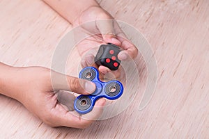 Person hand holding the fidget spinner and fidget cube