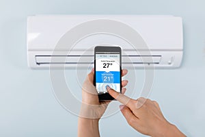 Person Hand Holding Mobilephone Near Air Conditioner