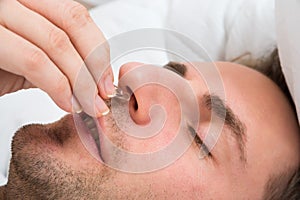 Person hand inserting nose clip device into nose