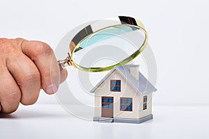 Person Hand With Magnifying Glass And Miniature House