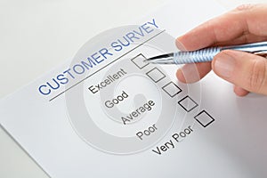Person hand with pen over customer survey form