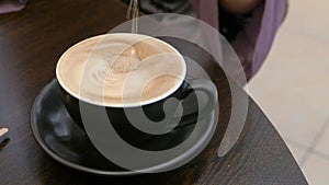 Person hand stirring coffee with spoon.