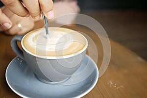 person hand stirring coffee with spoon.