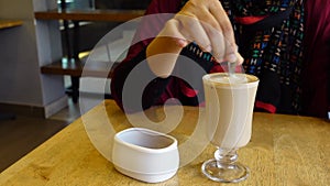 person hand stirring coffee with spoon.