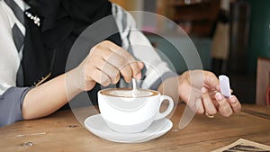 person hand stirring coffee with spoon.